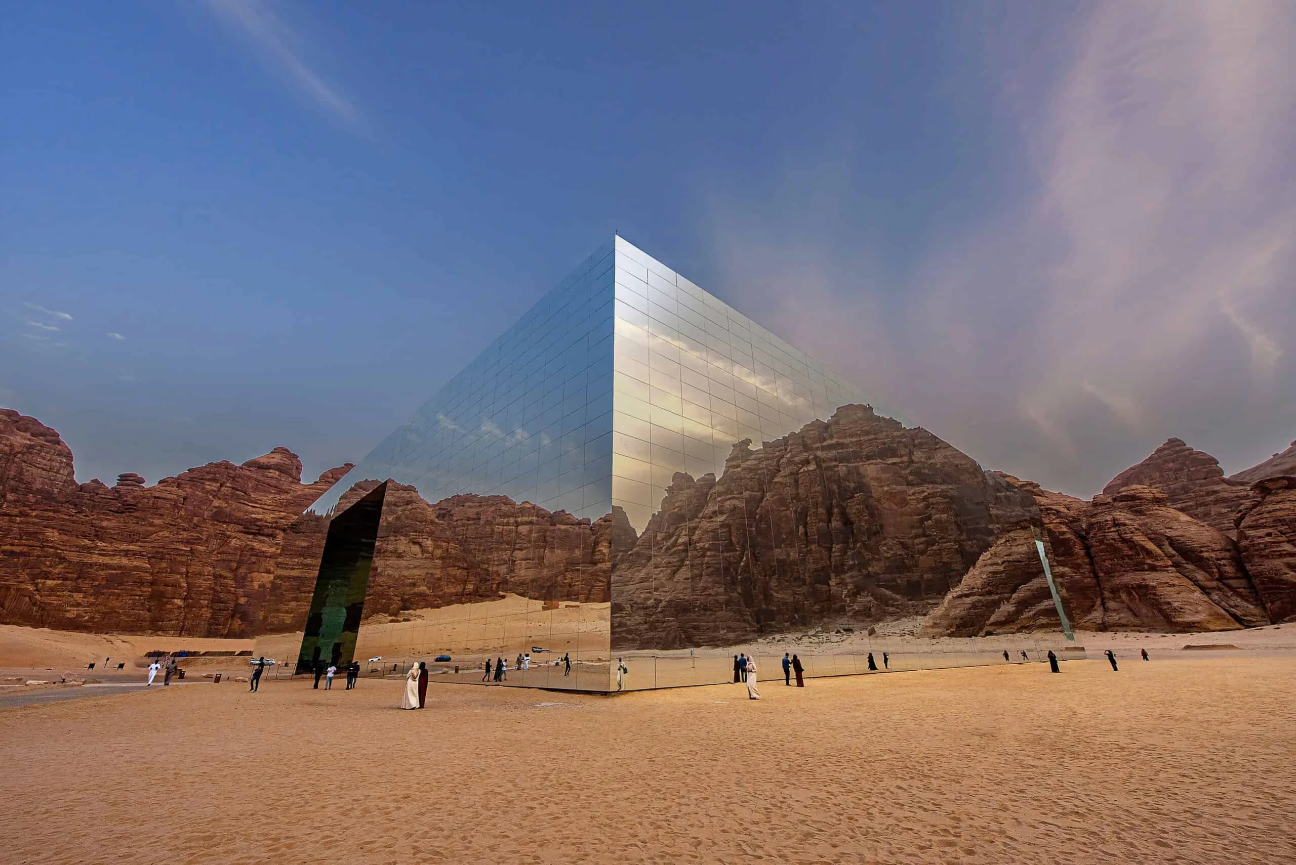 Mirror cube standing in a rocky desert at dusk